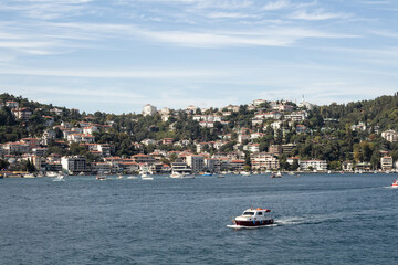 View of a small boat on Bosphorus and Bebek neighborhood on European side of Istanbul. It is a sunny summer day. Beautiful travel scene.