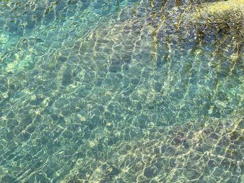 Sea water turquoise green shiny surface. Clear glittering sea background.