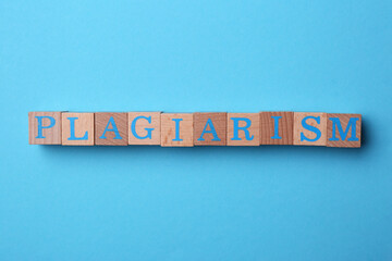 Word Plagiarism made of wooden cubes with letters on light blue background, top view