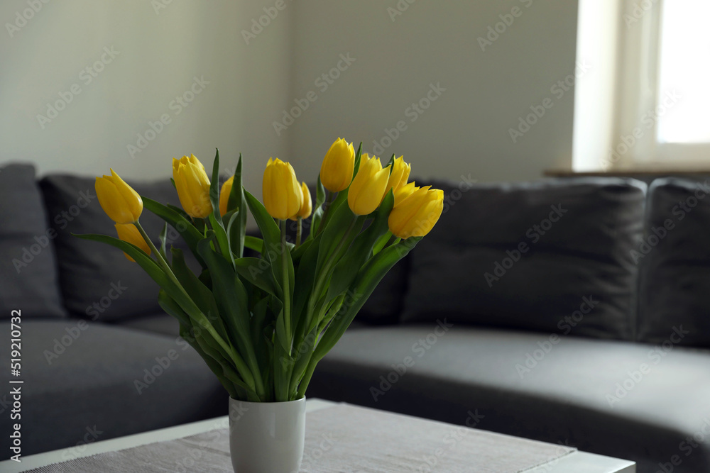 Wall mural Bouquet of beautiful yellow tulips on table in living room, space for text