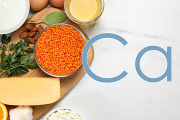 Different fresh products with high amounts of easily absorbable calcium on white marble table, flat lay