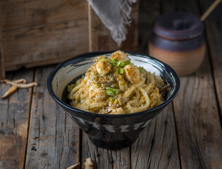 Shrimp udon served in a bowl isolated on wooden background side view of japanese food