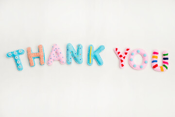 Stuffed felt letters with decorations. Word "Thank you" on isolated neutral background. Handmade crafts. Flat lay.