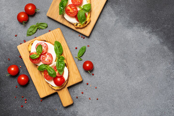 Fresh aromatic caprese sandwiches on grey rustic background top view, copy space for your design.