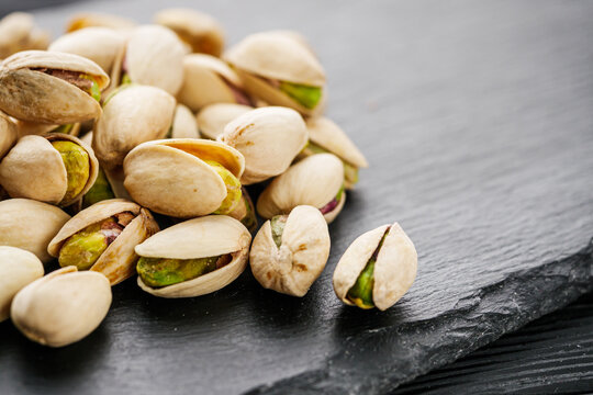 fresh salted pistachios on a black stone wooden rustic background