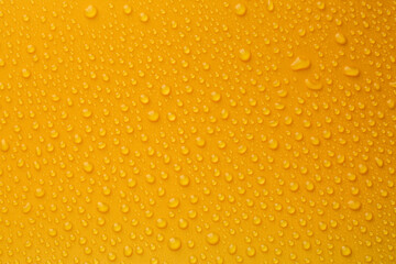 Water drops on orange background, top view