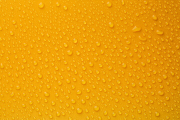 Water drops on orange background, top view