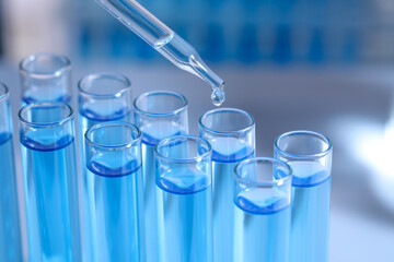 Dripping reagent into test tube on blurred background, closeup. Laboratory analysis