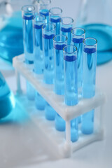 Test tubes with blue liquid on light background, closeup
