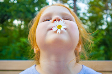 a beautiful little girl with a daisy. the face of a girl with a daisy