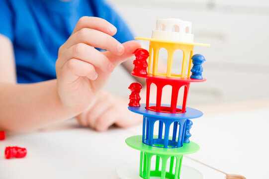 Balancing table game for kids. Tower with colorful figures. Boy plays an educational game to develop coordination and concentration. Early education, fine motor skills.