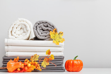 White and gray linen, bed sheet and two folded towels on a table with halloween decor.
