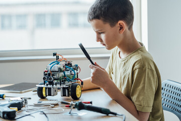 Shot of a cute young boy building robot constructor, engineering, playing and looking through the...