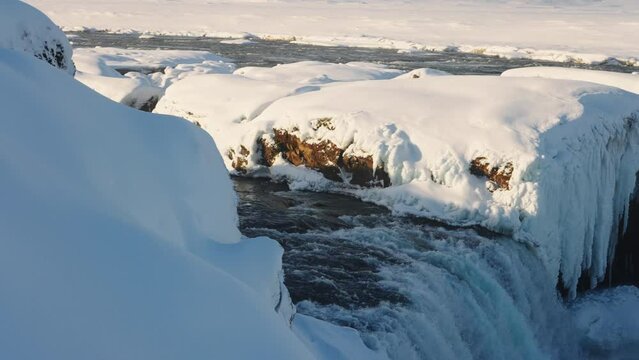 sunlit godafoss waterfall and Skjalfandafljot river with snow