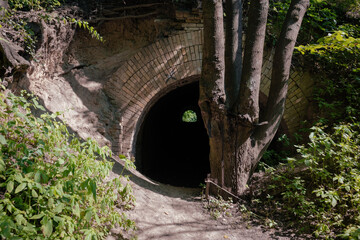 An old brick tunnel through an earthen hill. Ancient brick entrance to the dungeon