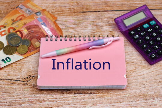 Das Wort Inflation auf einem Notizblock mit Taschenrechner und Euro Banknoten.