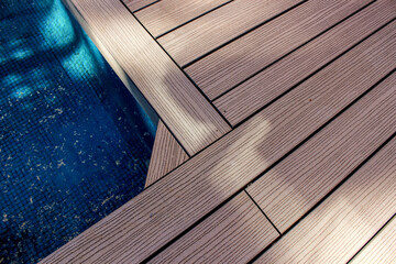 Refreshing swimming pool with crystal-clear blue water, inviting you to take a dip on a sunny day. Wooden deck in home garden surrounds the pool area.