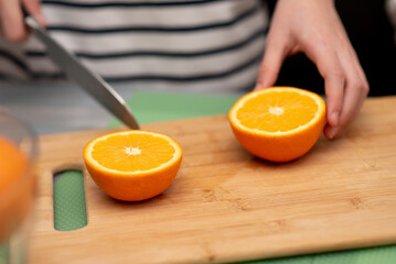 Two cute sister girls are making orange fresh juice.Hands close-up. They are in the kitchen at home. Family. Fresh fruit.