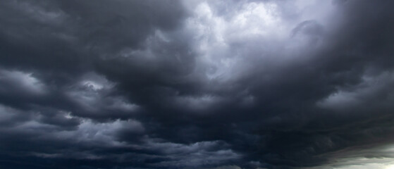 The dark sky with heavy clouds converging and a violent storm before the rain.Bad or moody weather sky.