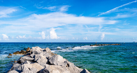 panoramic view of seawall in ocean with clouds in blue sky