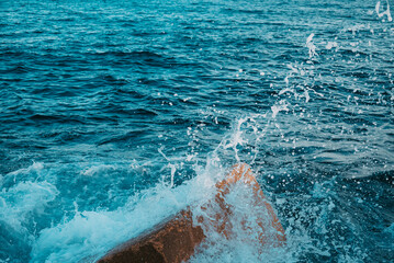 Close-up of water splashes against the breakwaters on the Balearic Sea. View from the pier on the beach of Barcelona, Spain.