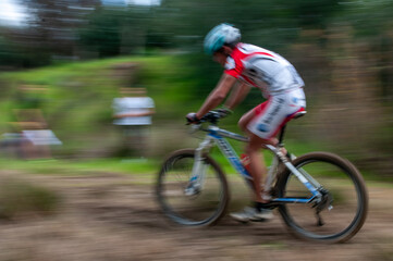 Cyclist pedalling in a racing mountain bike outdoors.  Unrecognized athlete on a bicycling race competition in motion