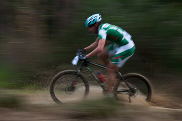Obraz premium Cyclist pedalling in a racing mountain bike outdoors. Unrecognized athlete on a bicycling race competition in motion