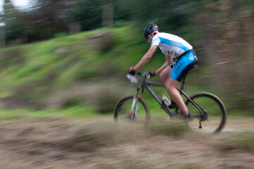 Fototapeta premium Cyclist pedalling in a racing mountain bike outdoors. Unrecognized athlete on a bicycling race competition in motion