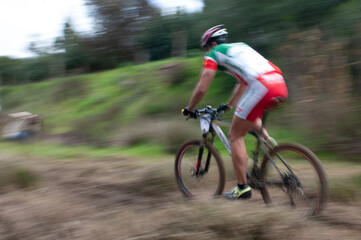 Cyclist pedalling in a racing mountain bike outdoors.  Unrecognized athlete on a bicycling race competition in motion