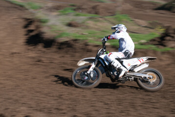 Unrecognized athlete riding a sports motorbike on  motocross racing compatition