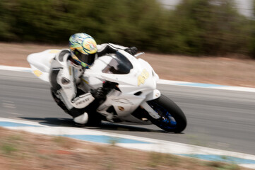 White sports motorcycle and rider racing fast on a track