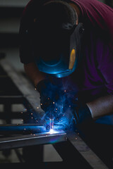 Industry worker welding iron pieces at work