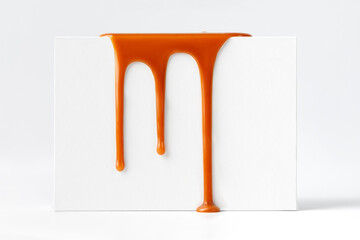 Dripping caramel drops of sweet caramel sauce on white podium on white background.  Melted caramel...