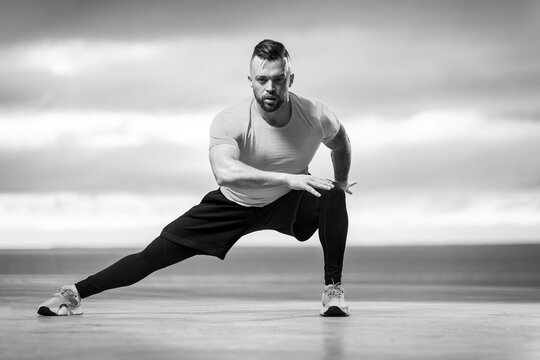 Athletic man doing fitness exercises on the ocean beach