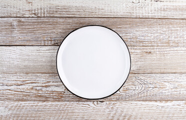 Empty ceramic plate on wooden background. Top view.