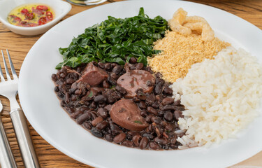 Typical brazilian feijoada with rice, pepper, farofa, kale and cracklings
