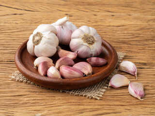Garlic bulb and cloves on a plate over wooden table