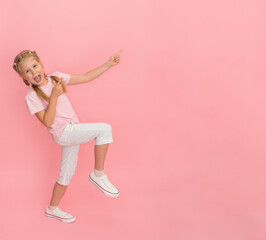 Full length portrait of happy girl on pink background showing pointing to empty copyspace.