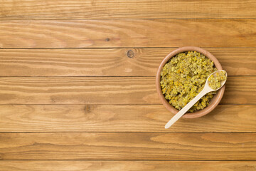 Obraz na płótnie Canvas Dried immortelle herbs in bowl on wooden background, top view