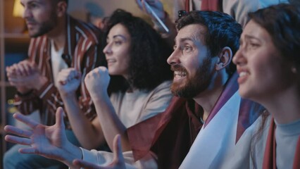 Lifestyle portrait of football fans watching soccer football game on TV at home couch. Nervous guys supporting favorite team and awaiting for the goal. Entertainment concept.