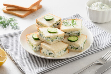 Homemade English tea cucumber sandwiches with cream cheese and dill on white background. Close up.