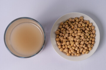 Soy bowl and soy drink on a glass, on a white table, top view