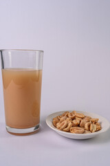 Peanut bowl and peanut drink on a glass, on a white table