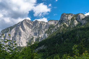 Stunning view of the steep cliff of Trisselwand above Altaussee lake on a sunny summer day with blue sky cloud, Salzkammergut-Ausseerland region, Styria, Austria - 519228176