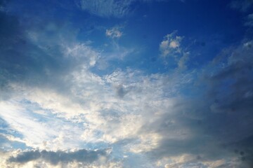 Blauer Himmel mit weißem dramatsichem Wolkengebilde bei Sonne am Abend im Sommer