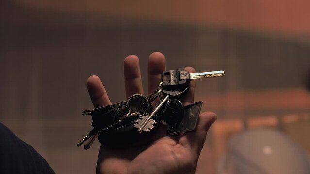 Man in the room pulls out a large bunch of keys from his pants pocket. Close-up. Cinematic