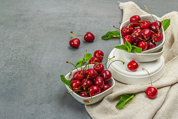 Ripe sweet cherries with fresh mint leaves, traditional summer fruits. Trendy stands, vintage napkin