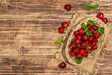 Ripe sweet cherries with fresh mint leaves, traditional summer fruits. Trendy light, vintage napkin