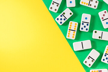 White dominoes with colorful dots on a yellow-green background, top view. Board game. Place for text