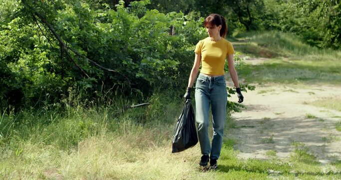 Woman cleaning up the forest and collecting trash, female picking up a plastic bottle